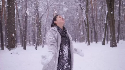 Girl spinning around while throwing snow up laughing at winter trees background. Stock Footage 84819607