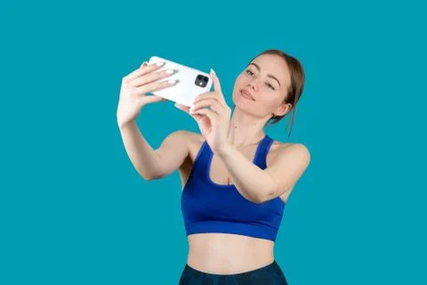 Girl in sports uniform looks at the phone on a blue background Stock Photos