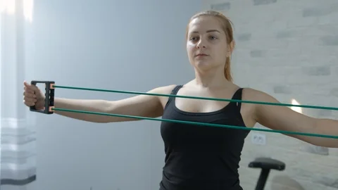 Girl in sportswear doing exercise using a rubber expander Stock Footage 128148409