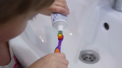 Girl squeezes toothpaste onto a toothbrush Stock Footage 141747834