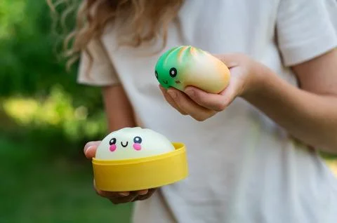 Girl squeezing cute dumpling squishy stress toys in garden Stock Photos