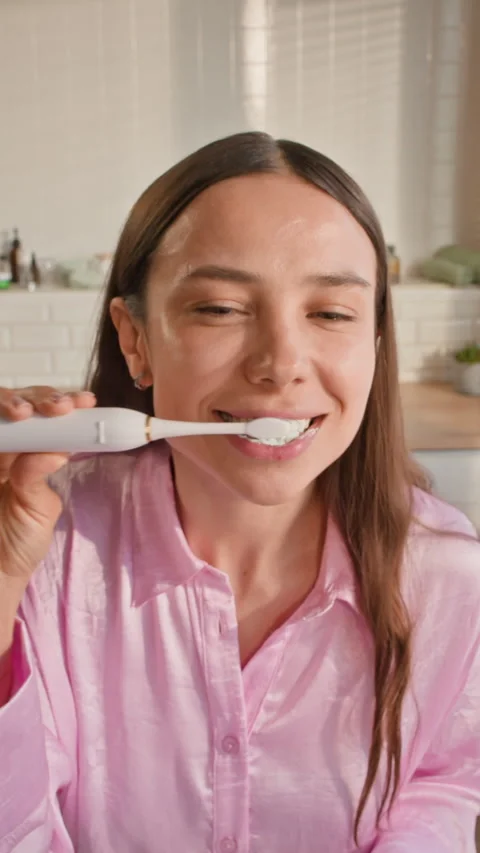 Girl Squeezing Toothpaste on Electric Toothbrush and Brushing Her Teeth Stock Footage 313506479