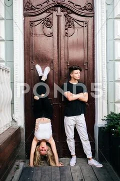 Girl standing on the hands, a guy beside Stock Photos