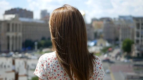 The girl is standing with her back to the camera. She has very long hair Stock Footage 99409582