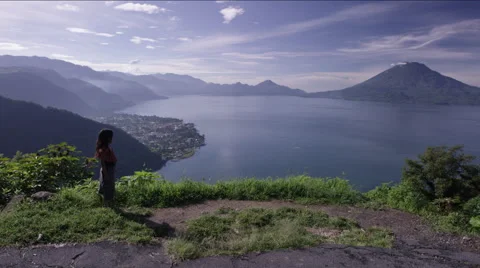 Girl standing on a hill and looking at the beautiful lake Stockbeeldmateriaal 63055152