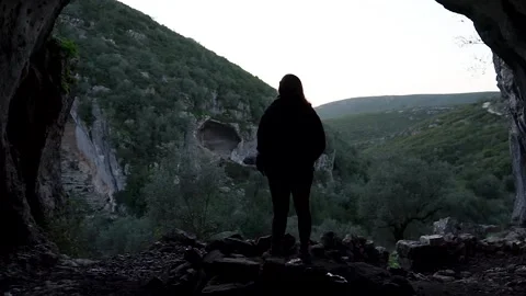 Girl standing inside a cave observing the beautiful landscape background. Stock Footage 150949560