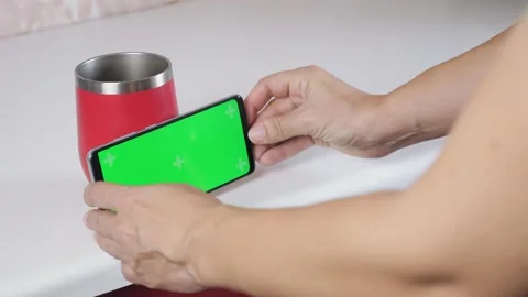 The girl is standing in the kitchen, drinking coffee and watching a video on the Stock Footage 208961973