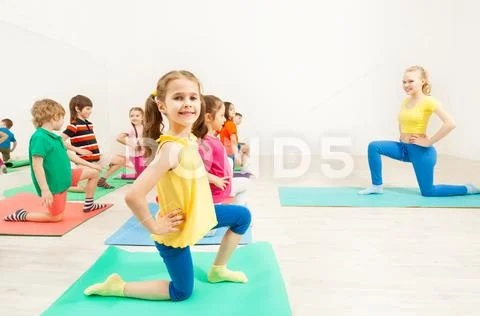 Girl standing on knee during gymnastic activity Stock Photos