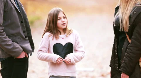 Girl standing in park and talking with parents Stock Footage 59554259