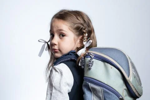 The girl is standing with a school bag and looking at the camera Stock Photos