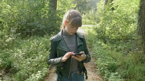 Girl stands on trail in woods using phone to navigate, medium 動画素材 124363589