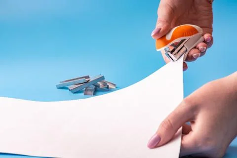 Girl stapler fastens sheets of documents from paper in office. Copy space. Sp Stock Photos