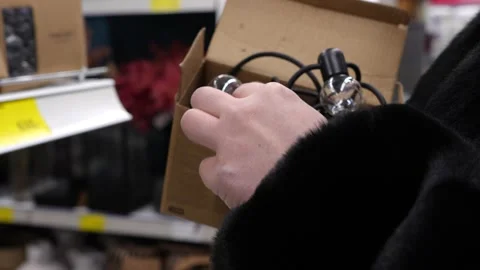 A girl in a store examines an electronic wireless garland of small light bulbs Stock Footage 232855010