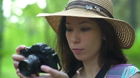 Girl in straw hat flips through photos on the camera. on nature. Stock Footage 80283302