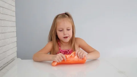 Girl stretching orange slime to the side... | Stock Video | Pond5