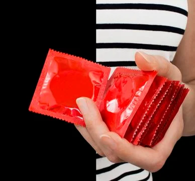 Girl with a striped shirt holding many red condoms. Stock Photos