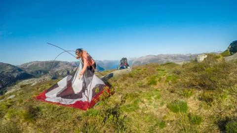 A girl struggles to out the tent up together. She is camping in the wildernes Stock Photos