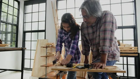 Girl student practicing woodworking from elderly carpenter build objects Stock Footage 159664760