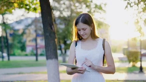 Girl student using digital tablet prints messages on city street. Freelancer Stock Footage 305098640