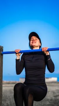 Girl suffering doing pullups Stock Photos