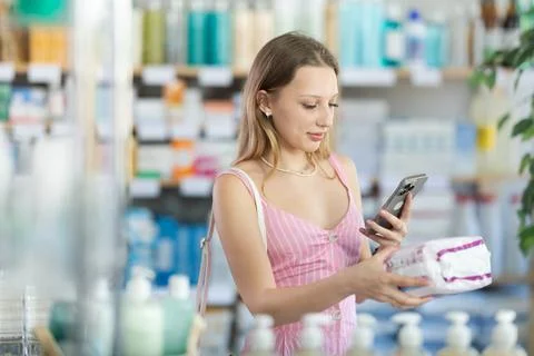 Girl in summer clothes scans code on package of feminine pads to check Foto stock