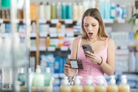 Girl in summer clothes scans code on cosmetics to check expiration date Stock Photos