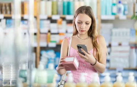 Girl in summer clothes scans code on package of pills to check expiration date Stockfoto's