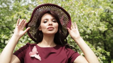 Girl in a summer hat posing in front of a blooming garden, flowering Apple trees Vídeo Stock 108826973