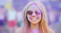 Girl in sunglasses covered in colorful dyes smiling, blowing air kiss to camera 4k or 4k+ Resolution