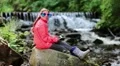 Girl in sunglasses in the shape of hearts with tablet pc sits near small river HD Footage