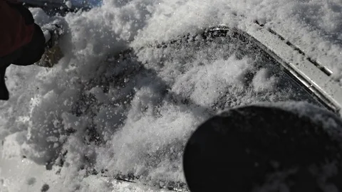 Girl sweeps snow from the body of the car Stock Footage