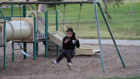 Girl swinging while on cellphone Stock Footage 154992220