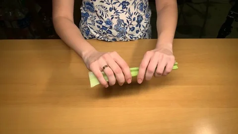 Girl at the table cleans from the rind of the celery Stock Footage 124209830