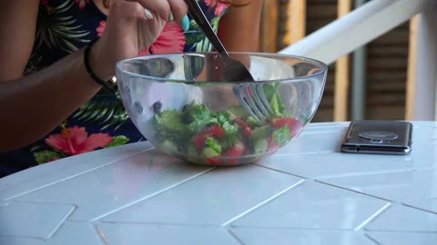 Girl at the table eats vegetable salad from glass tableware Stock Footage 99562008