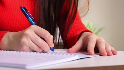 A girl at the table writes with a pen in a notebook Stock Footage 252532721