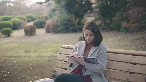 Girl with a tablet in the park Stock Footage 99207386