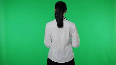 Girl with tablet stand back to camera turns around waves hand. Green background Stock Footage 115914524