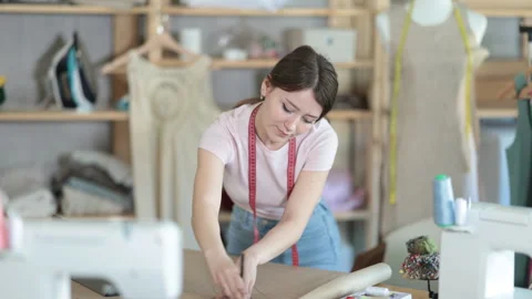 Girl tailor draws pattern on a sheet of paper in a sewing workshop Stock Footage 314764793