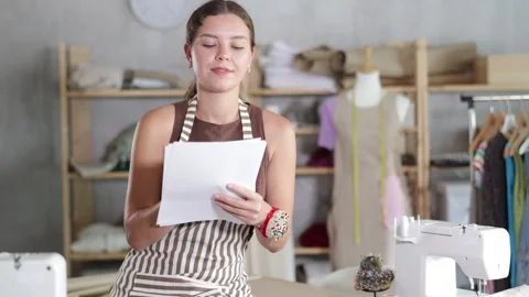 Girl tailor draws pattern on a sheet of paper in a sewing workshop Stock Footage 341377873