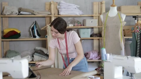Girl tailor draws pattern on a sheet of paper in a sewing workshop Stock Footage 341531493