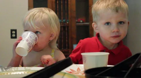 Girl takes a drink while sitting by a wiggly boy Stock Footage 40027630