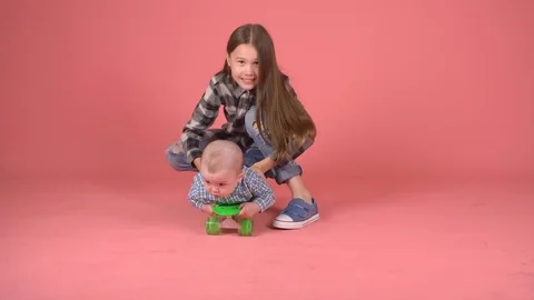 Girl takes her brother on a skateboard Stock Footage