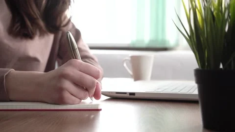 A girl takes notes in a notebook from her laptop. Stock Footage 171909393