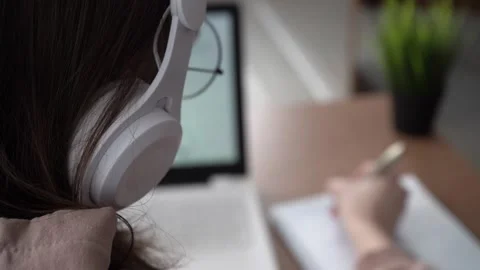A girl takes notes in a notebook from her laptop. back view Stock Footage 171909418
