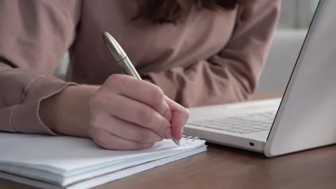 A girl takes notes in a notebook from her laptop. Stock Footage 172258900