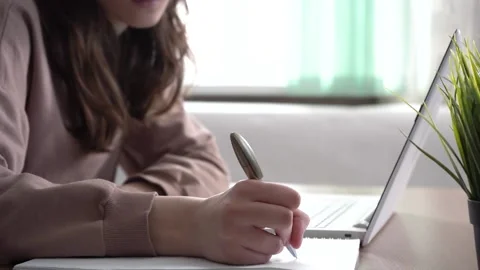 A girl takes notes in a notebook from her laptop. Stock Footage 173414532
