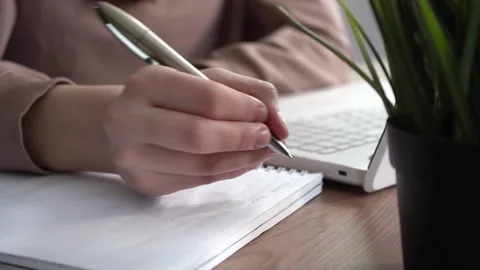 A girl takes notes in a notebook from her laptop. Stock Footage 173416683