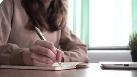 A girl takes notes in a notebook from her laptop. Stock Footage 182015326