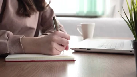 A girl takes notes in a notebook from her laptop. Stock Footage 182024343