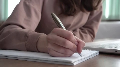 A girl takes notes in a notebook from her laptop. Stock Footage 182046615